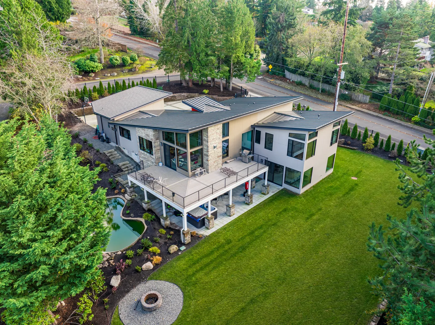 Aerial view of a modern custom home with wraparound deck and landscaped yard