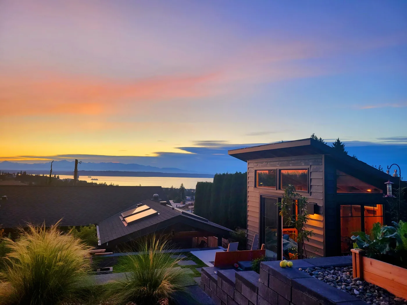 Modern build with an integrated deck and panoramic water views at dusk