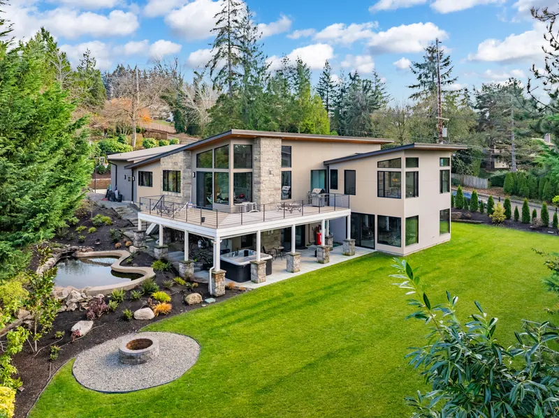 Backyard of a modern custom home with a covered deck, lawn and fire pit