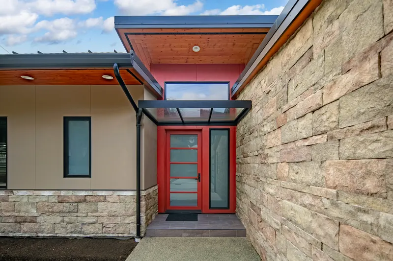 Red front door framed by stone and Hardie panel