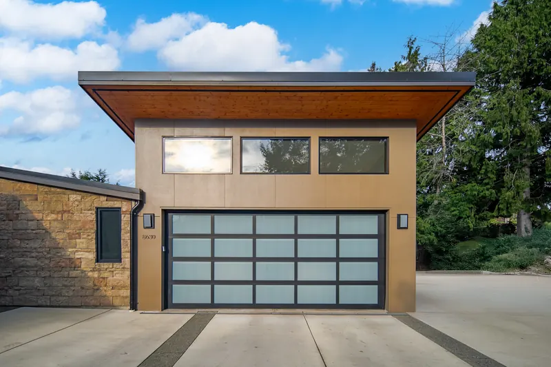 Garage with a glass-panel door under a wood soffit