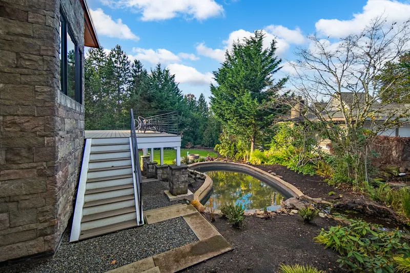 Exterior stairs beside a landscaped pond with a footbridge