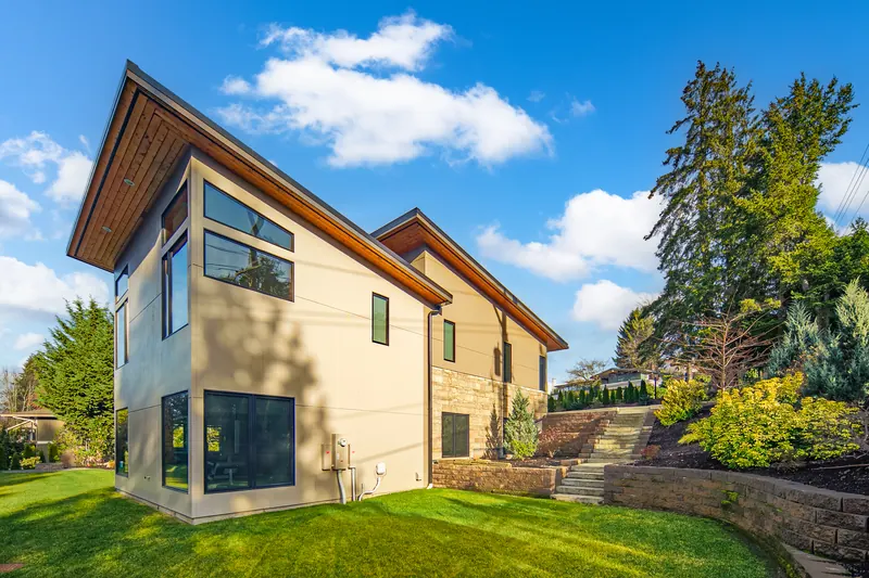 Corner of the home with large windows and landscaping