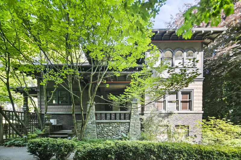 Front of the historic home with a covered porch and gardens