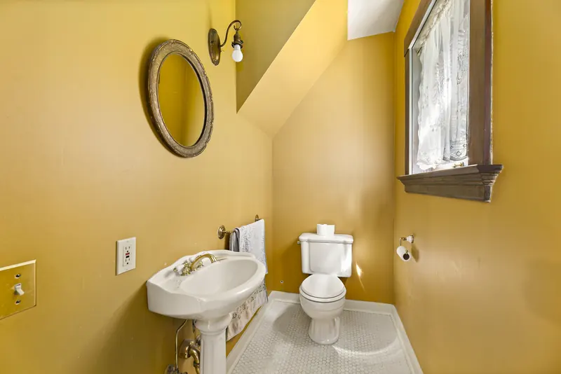 Powder room with a pedestal sink and an oval mirror