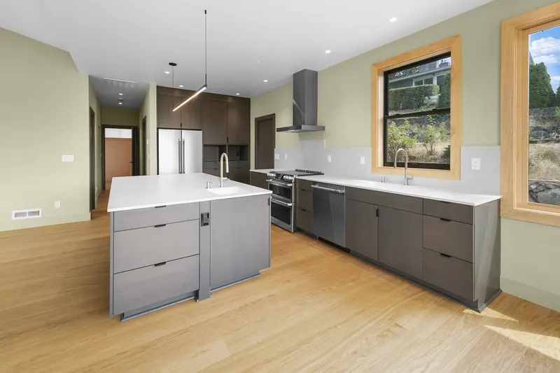 Open kitchen with a large island, dark cabinetry and windows