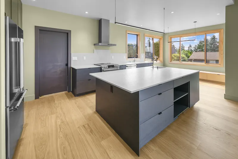 Kitchen island with dark base cabinets and a white quartz top