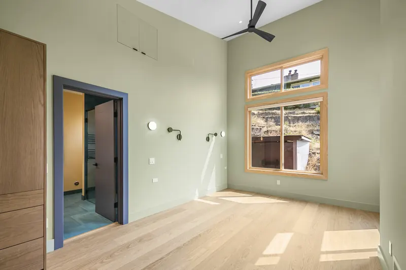 Room with a vaulted ceiling, ceiling fan and a large window
